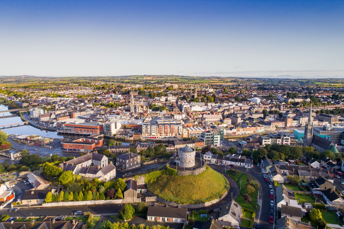 Aerial view of Drogheda with Millmount Martello tower on its grassy mound in the foreground, the River Boyne to the left and church spires rising across the town.